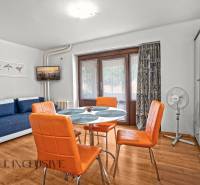 NA PREDAJ APARTMÁNOVÝ DOM VO VEĽKOM MEDERI - Svetlá izba s oranžovými stoličkami, modrým gaučom a podlahou s dreveným dekorom.