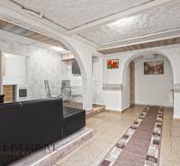 NA PREDAJ APARTMÁNOVÝ DOM VO VEĽKOM MEDERI - Interiér s čiernou sedačkou, stolom, stoličkami a oblúkovými priechodmi v Hotely a penzióny.