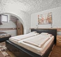 NA PREDAJ APARTMÁNOVÝ DOM VO VEĽKOM MEDERI - Štýlová hotelová izba s oblúkovým stropom, veľkou posteľou a obrazom na stene.