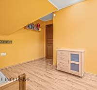 NA PREDAJ 6-IZBOVÝ POSCH. RODINNÝ DOM, HORNÉ SALIBY - Izba v rodinnom dome s podlahou s dreveným dekorom, žltými stenami a dreveným nábytkom.