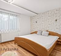 NA PREDAJ 6-IZBOVÝ POSCH. RODINNÝ DOM, HORNÉ SALIBY - Spálňa v rodinnom dome s posteľou a podlahou s dreveným dekorom. Tapeta s kvetinovým vzorom.