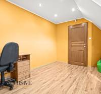 NA PREDAJ 6-IZBOVÝ POSCH. RODINNÝ DOM, HORNÉ SALIBY - Miestnosť v rodinnom dome s podlahou s dreveným dekorom, stôl, kreslo, zelený vak.