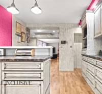 NA PREDAJ 6-IZBOVÝ POSCH. RODINNÝ DOM, HORNÉ SALIBY - Kuchyňa rodinného domu s podlahou s dreveným dekorom a výraznou ružovou stenou.