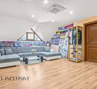 NA PREDAJ 6-IZBOVÝ POSCH. RODINNÝ DOM, HORNÉ SALIBY - Pohodlný obývací priestor v rodinnom dome s podlahou s dreveným dekorom a futbalovými šálmi.