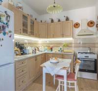 ZĽAVA - 3 IZBOVÝ RODINNÝ DOM, BLÍZKO CENTRA DUN.STREDY - Kuchyňa v rodinnom dome so svetlými skriňami, dekorovaná podlaha a stôl so stoličkami.