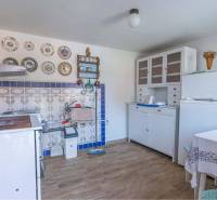 ZĽAVA - 3 IZBOVÝ RODINNÝ DOM, BLÍZKO CENTRA DUN.STREDY - Rustikálna kuchyňa v rodinnom dome so starožitnými taniermi a kachľami, podlaha s dreveným dekorom.