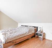 NA PREDAJ RODINNÉ DOMY S GARÁŽOU, DUNAJSKÁ STREDA - Spálňa v rodinnom dome s posteľou, nočným stolíkom a svietidlom pod šikmým stropom.