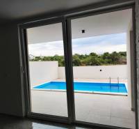 VRSI - dvojdom s bazénom a záhradou - Výhľad z rodinného domu na terasu s bazénom, podlaha s dreveným dekorom.