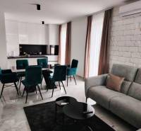 VRSI - dvojdom s bazénom a záhradou - Obývačka s kuchyňou v rodinnom dome; mramorová podlaha, biele skrinky, zelené stoličky.