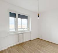 Exkluzívne predáme pekný 3-izbový byt vo Vajnoroch - Izba v 3-izbovom byte s podlahou s dreveným dekorom a bielymi stenami.