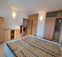 Prenájom pekného a priestranného 4-izbového bytu vo Svite - Spálňa v 4-izbovom byte s dreveným dekorom nábytku a posteľou bez matraca.