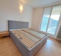 Prenájom pekného a priestranného 4-izbového bytu vo Svite - Spálňa v 4-izbovom byte s posteľou a nočným stolíkom, podlaha s dreveným dekorom.