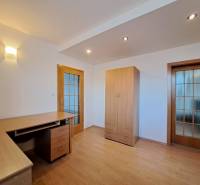 Prenájom pekného a priestranného 4-izbového bytu vo Svite - Izba v 4-izbovom byte s podlahou s dreveným dekorom, stolom a skriňou.