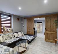 Rodinný dom Unín s pozemkom 941 m2 - Obývačka s pohodlnou sedačkou, posuvnými dverami a podlahou s dreveným dekorom.