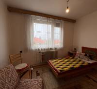 Exkluzívny PREDAJ 4 izbového rodinný domu s garážou, Zlatná na Ostrove - Izba s posteľou, kreslom a dekoratívnym kobercom na stene v rodinnom dome.