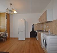 EXKLUZÍVNY PREDAJ - 1 izbový byt Revolučná Štvrť , Galanta - Kuchyňa v 1-izbovom byte s podlahou s dreveným dekorom, jedálenským stolom a spotrebičmi.