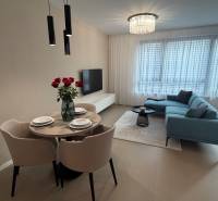 Exk. prenájom lux. 2 iz bytu Rezidencia Blumental - Obývacia izba v 2-izbovom byte s&nbsp;šedou sedačkou, jedálenským stolom a&nbsp;podlahou s dreveným dekorom.