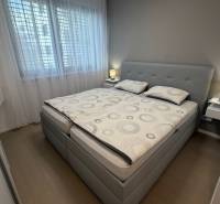 Exk. prenájom lux. 2 iz bytu Rezidencia Blumental - Spálňa v 2-izbovom byte s posteľou, nočnými stolíkmi a podlahou s dreveným dekorom.