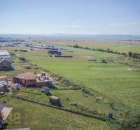 Jedinečný stavebný pozemok v krásnej lokalite Tatranské Smaragdy - Pozemky - bývanie v Mlynici; rozostavané domy a rozsiahle polia pod slnečnou oblohou.