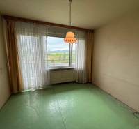 Ponúka na predaj 3 izbový byt v Detve - Izba so zelenou podlahou a veľkým oknom v 3-izbovom byte.