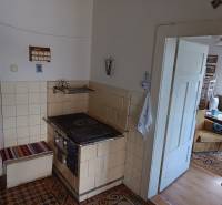 Hospodárska usadlosť s 3,6 hektárovým pozemkom na samote Nová Baňa - Starší sporák v kuchyni rodinného domu, vedúci do obývacej izby s nábytkom.