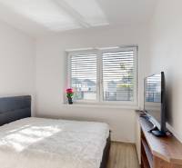 , predaj 4 izb. novostavby zariadeného RD, Jarná, Hviezdoslavov - Spálňa s posteľou, televízorom na poličke a podlahou s dreveným dekorom v rodinnom dome.