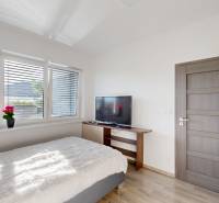 , predaj 4 izb. novostavby zariadeného RD, Jarná, Hviezdoslavov - Spálňa v rodinnom dome so svetlými stenami, televízorom a podlahou s dreveným dekorom.