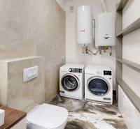 , predaj 4 izb. novostavby zariadeného RD, Jarná, Hviezdoslavov - Kúpeľňa s toaletou, práčkou a sušičkou, dekoratívne poličky a podlaha s dreveným dekorom.