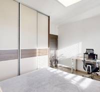 , predaj 4 izb. novostavby zariadeného RD, Jarná, Hviezdoslavov - Spálňa v rodinnom dome s veľkou skriňou, stolom a podlahou s dreveným dekorom.