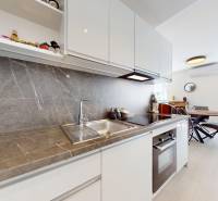 Krásny moderný 2 izbový byt v centre Bratislavy, nám. SNP - Kuchyňa v 2-izbovom byte so sivou pracovnou doskou, bielymi skrinkami a jedálenským kútom.