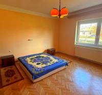 NA PREDAJ 5 izbový rodinný dom s veľkou záhradou v obci Iža - Spálňa v rodinnom dome s podlahou s dreveným dekorom a oranžovými stenami.