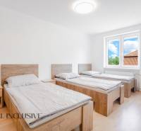 Na predaj 7-izb. RD s obchod. priestorom, Dun. Streda - Tri postele v izbe s podlahou s dreveným dekorom a veľkým oknom.