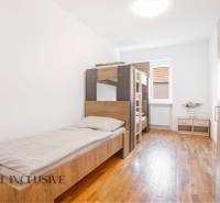 Na predaj 7-izb. RD s obchod. priestorom, Dun. Streda - Interiér spálne v budove s posteľami a podlahou s dreveným dekorom.