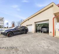 Na predaj 7-izb. RD s obchod. priestorom, Dun. Streda - Budova v Dunajskej Strede s automobilmi pred garážami a dopravnými značkami.