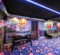 Na predaj 7-izb. RD s obchod. priestorom, Dun. Streda - Interiér budovy s graffiti na stenách, farebné koberce a stolný hokej.