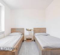 Na predaj 7-izb. RD s obchod. priestorom, Dun. Streda - Izba s dvoma posteľami, nočným stolíkom a podlahou s dreveným dekorom.