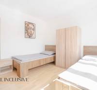 Na predaj 7-izb. RD s obchod. priestorom, Dun. Streda - Spálňa s dvomi posteľami a nábytkom, podlaha s dreveným dekorom, obraz na stene.