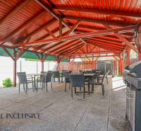 Na predaj 7-izb. RD s obchod. priestorom, Dun. Streda - Exteriérová terasa budovy v Dunajskej Strede s drevenou strechou a grilom.