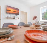 Na predaj 7-izb. RD s obchod. priestorom, Dun. Streda - Jedáleň v budove s dekoratívnym stolom, farebnými taniermi a televízorom na stene.