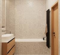 PROJEKT POD VINICOU | 4-IZB. BYT, UZAVRETÝ AREÁL, HOLOBYT, NOVOSTAVBA - Kúpeľňa so svetlým obkladom, drevenou skrinkou pod umývadlom a tmavým rebríkovým radiátorom.