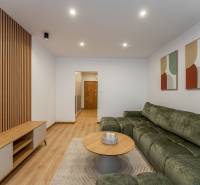 Kpt. Jaroša -  NOVINKA - MODERNÝ 2 IZBOVÝ BYT, 59 m2 + loggia. - Obývacia izba v 2-izbovom byte s pohovkou, stolíkom a podlahou s dreveným dekorom.