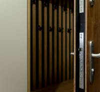 Kpt. Jaroša -  NOVINKA - MODERNÝ 2 IZBOVÝ BYT, 59 m2 + loggia. - Pohľad na otvorené vchodové dvere a vešiakovú stenu s podlahou s dreveným dekorom.