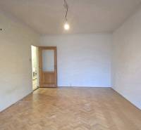 PREDAJ - 2-izbový byt pripravený na rekonštrukciu - Nitra, Chrenová - Izba v 2-izbovom byte s podlahou s dreveným dekorom a otvorenými dverami.