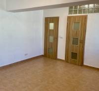 I Predaj Investičného 1-izbového bytu s veľkorysou loggiou  - Interiér 1-izbového bytu s keramickou podlahou a dvoma dverami s dreveným dekorom.