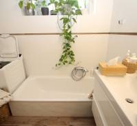 1-izb. kompletne zrekonštr.byt na Hradnom kopci (Lichardova ul.)  - Kúpeľňa v 1-izbovom byte s vaňou, práčkou a dreveným dekorom na podlahe.