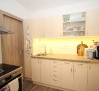 1-izb. kompletne zrekonštr.byt na Hradnom kopci (Lichardova ul.)  - Kuchyňa v 1-izbovom byte so svetlým nábytkom a podlahou s dreveným dekorom.