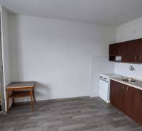 PREDAJ: 1 izbový byt - 37m2, s loggiou, Ružomberok - Za dráhou - Kuchyňa v 1-izbovom byte s tmavými skrinkami a podlahou s dreveným dekorom.