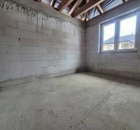 Novostavba 4i RD - Bungalov v obci Bidovce, KE-okolie - Betónová podlaha, nepomaľované tehly a drevené trámy v interiéri rodinného domu.