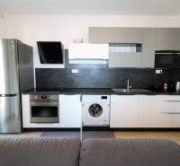 NUERA︱ SLNEČNICE- slnečný 2izbový byt s výhľadom na hrad - Kuchyňa v 2-izbovom byte so sivými skrinkami, spotrebičmi a podlahou s dreveným dekorom.