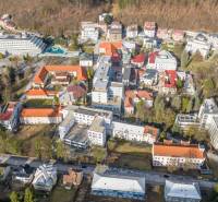 Exkluzívny investičný  pozemok Trenčianske Teplice, 1244m2 - Letecký pohľad na Trenčianske Teplice, Hurbanovu ulicu s komerčnými pozemkami a okolím.